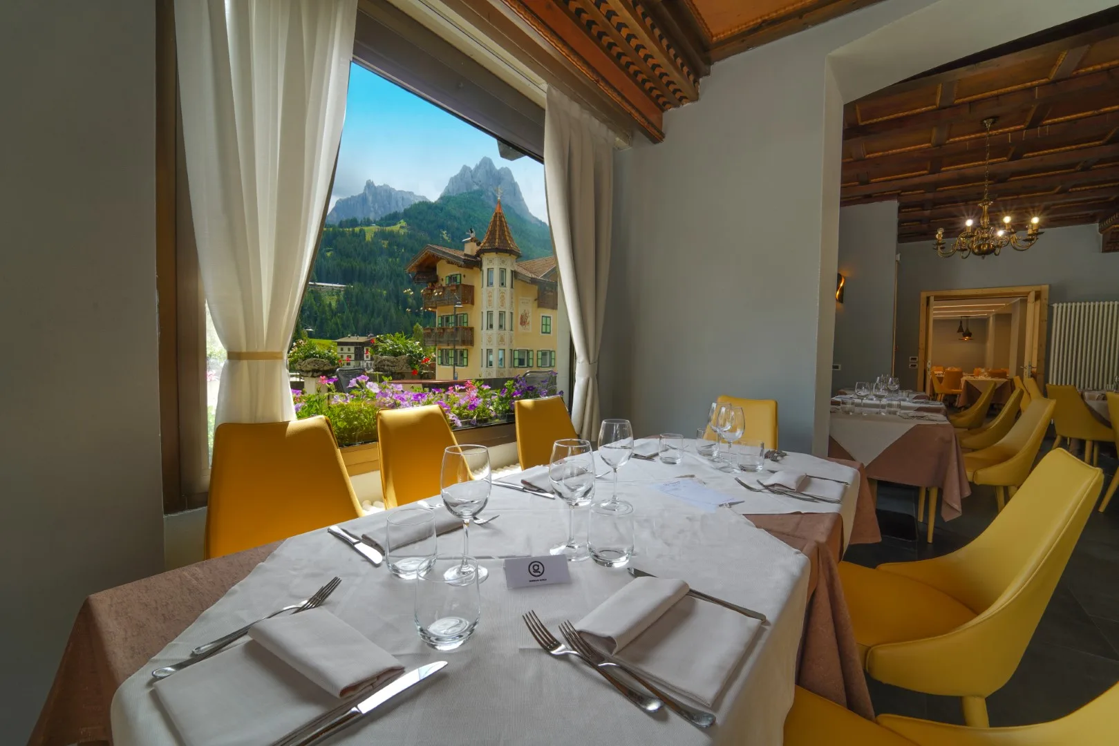 Tavolo del ristorante apparecchiato con vista sulle Dolomiti dalla finestra