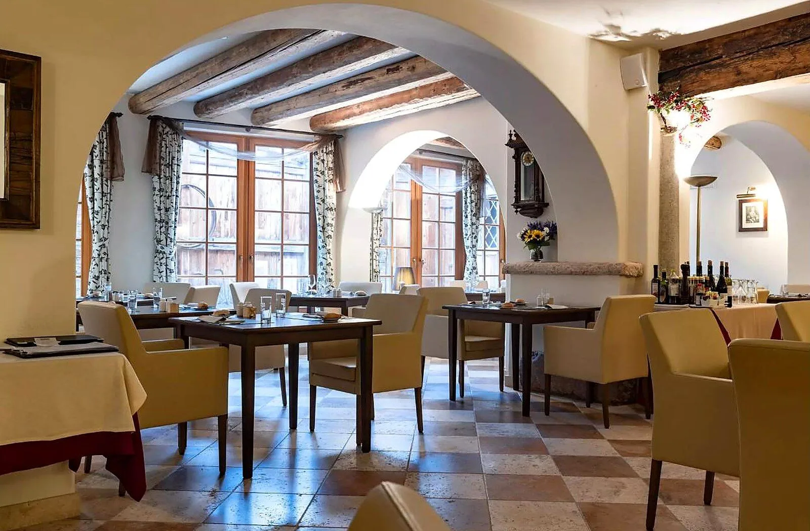 Sala ristorante con archi, travi a vista e tavoli apparecchiati accanto alle finestre