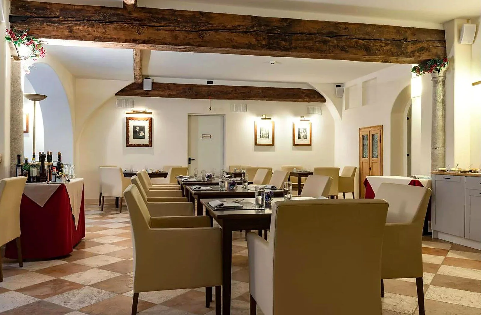 Sala da pranzo con travi antiche, colonne in pietra e tavoli con sedie beige