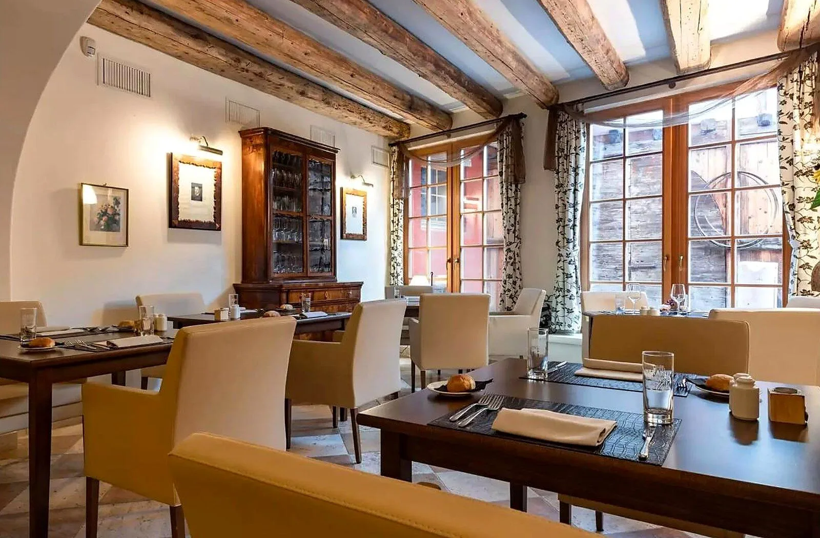 Elegante sala ristorante con travi a vista, credenza antica e tavoli apparecchiati