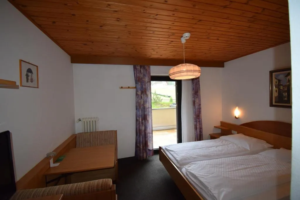 Camera matrimoniale con soffitto in legno, scrivania e uscita sul balcone
