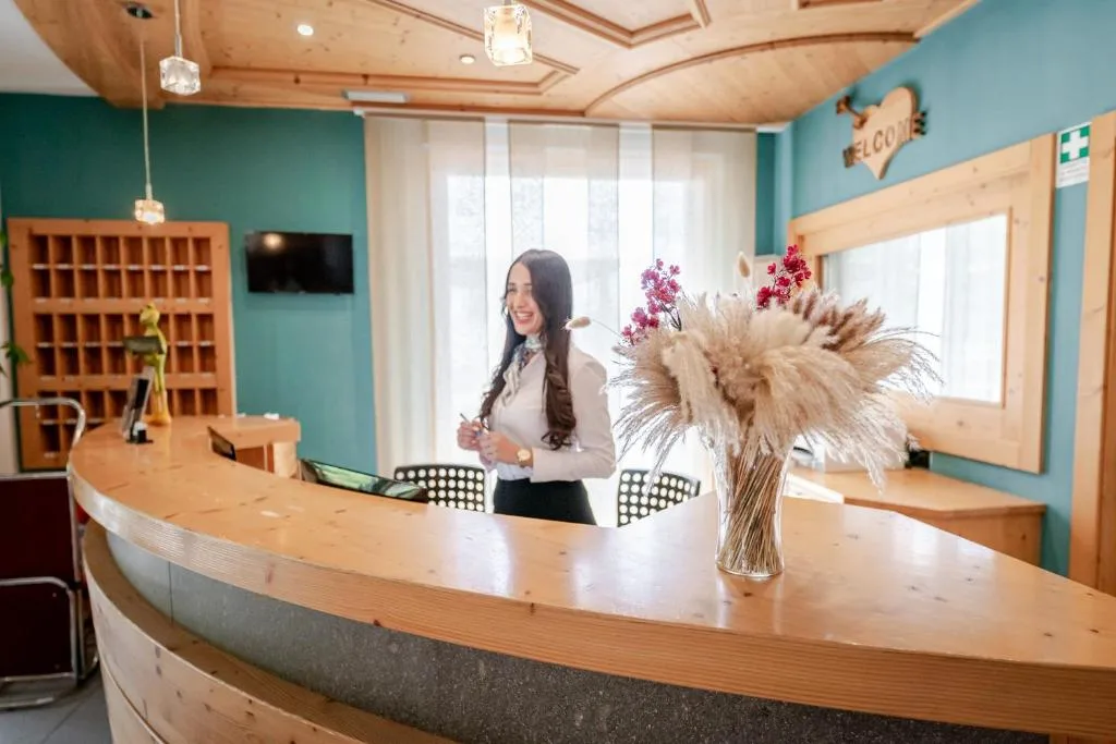 Reception dell'hotel con bancone in legno e receptionist sorridente