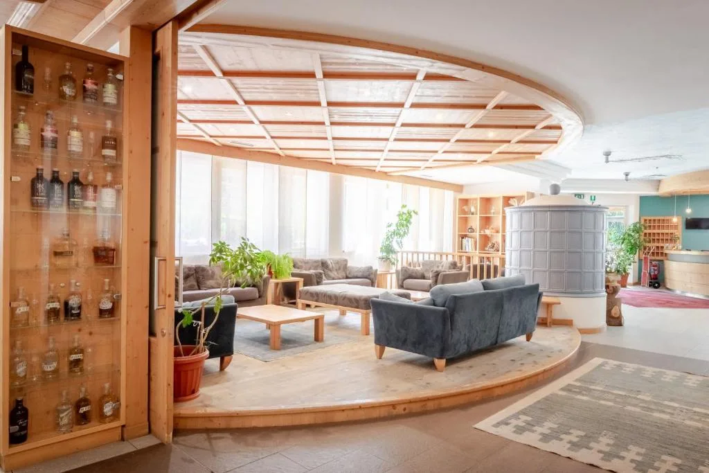 Hall dell'hotel con divani, stufa in maiolica e soffitto in legno