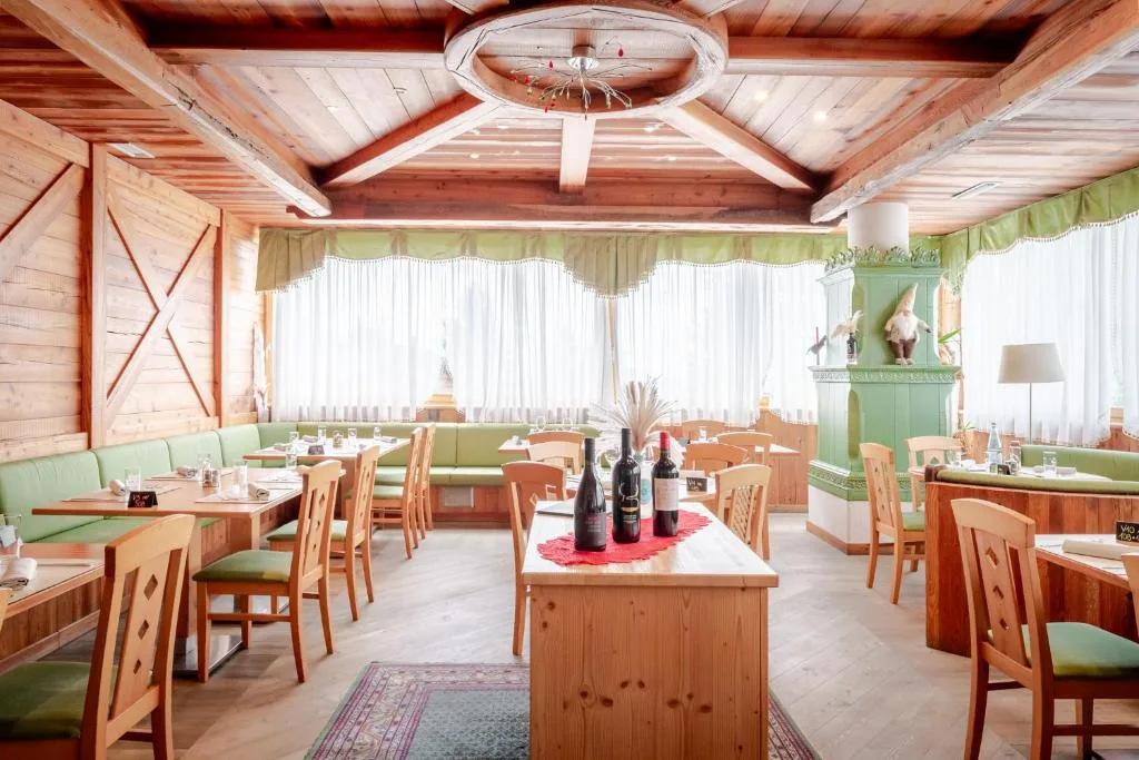 Sala ristorante in stile alpino con panche verdi e stufa in maiolica