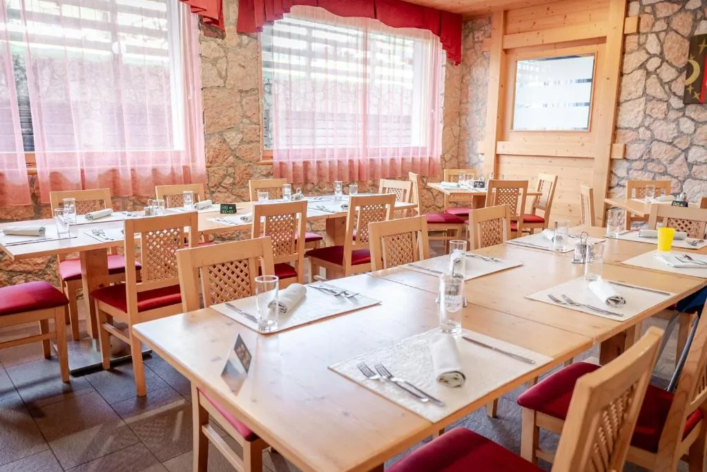 Sala da pranzo con pareti in pietra, tavoli apparecchiati e sedie rosse