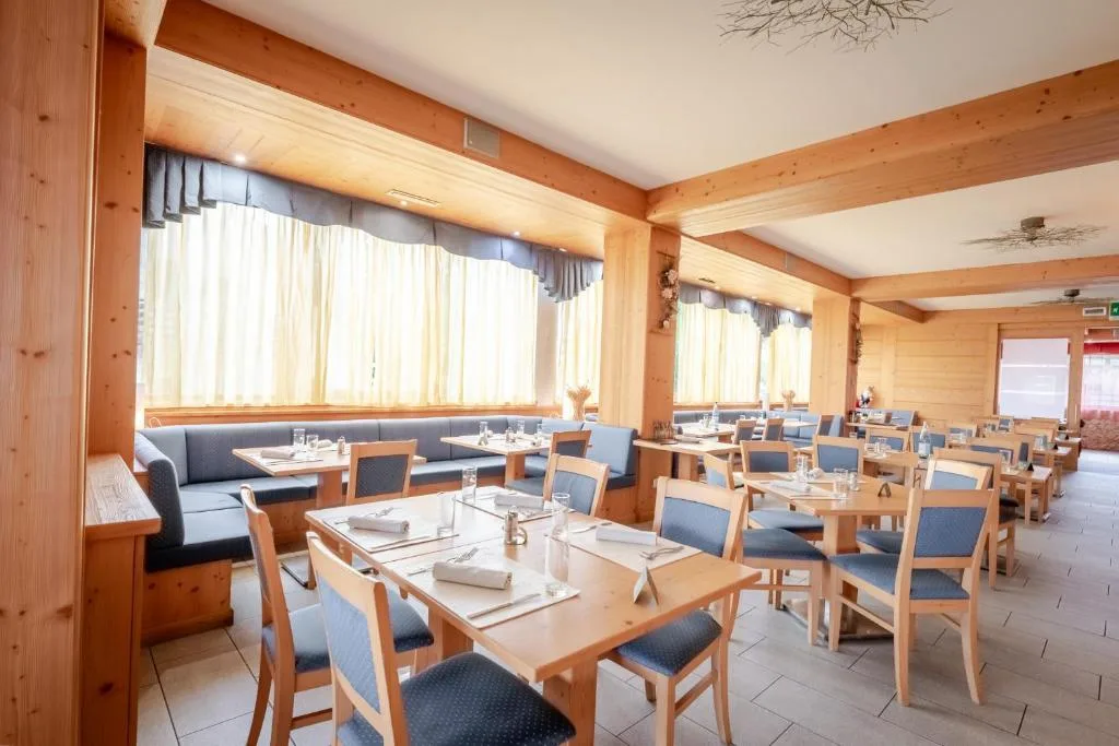 Sala ristorante luminosa con travi in legno, tavoli e panche blu