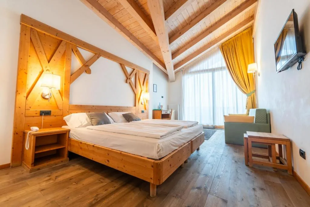 Camera mansardata con soffitto in legno, letto matrimoniale e poltrona