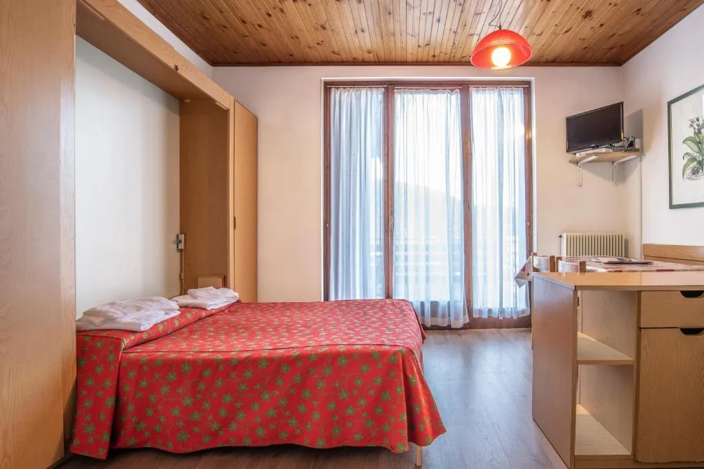 Camera luminosa con letto matrimoniale, scrivania e grande finestra