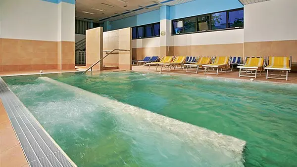 Piscina termale interna con idromassaggio e lettini colorati sul bordo