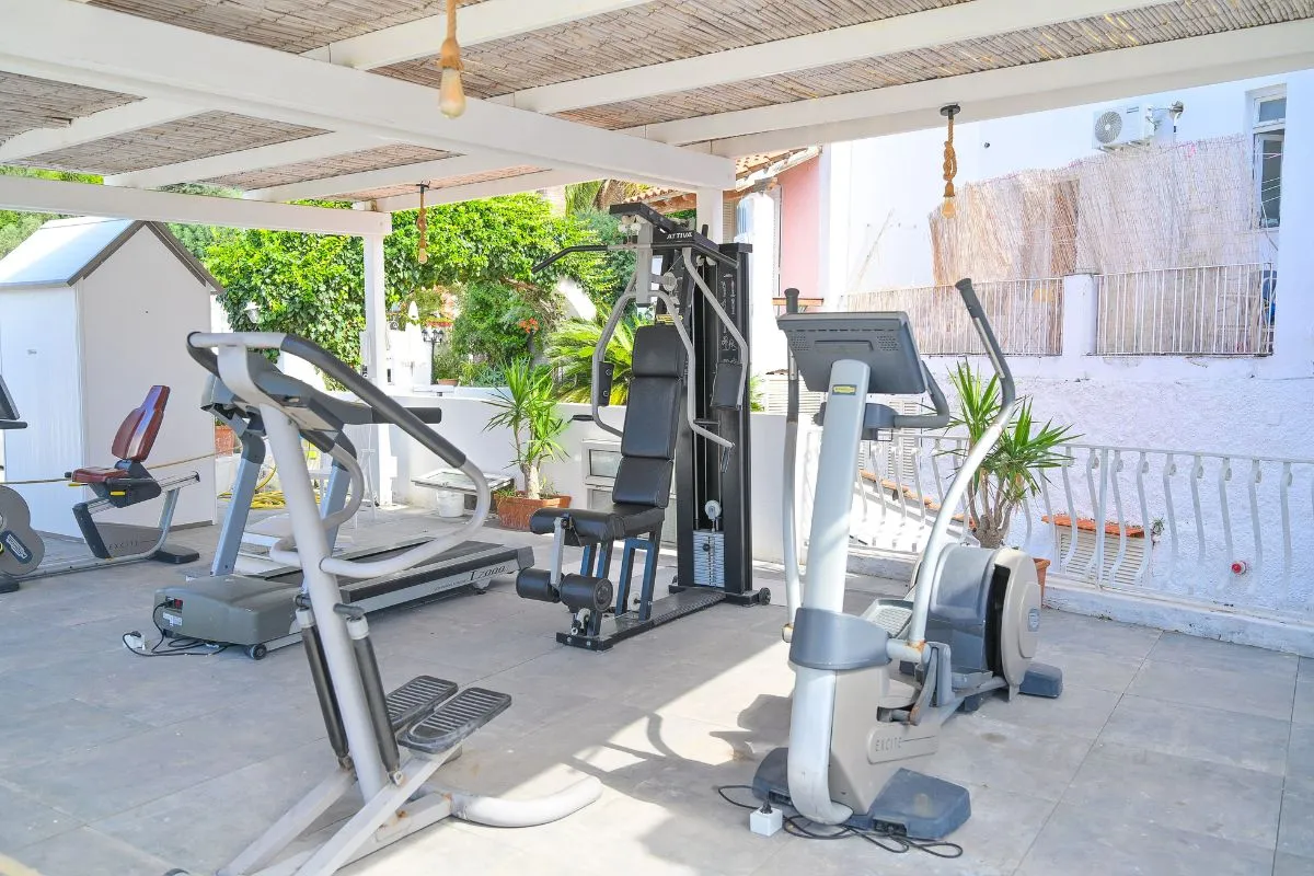 Area fitness all'aperto con attrezzi da palestra sotto un pergolato