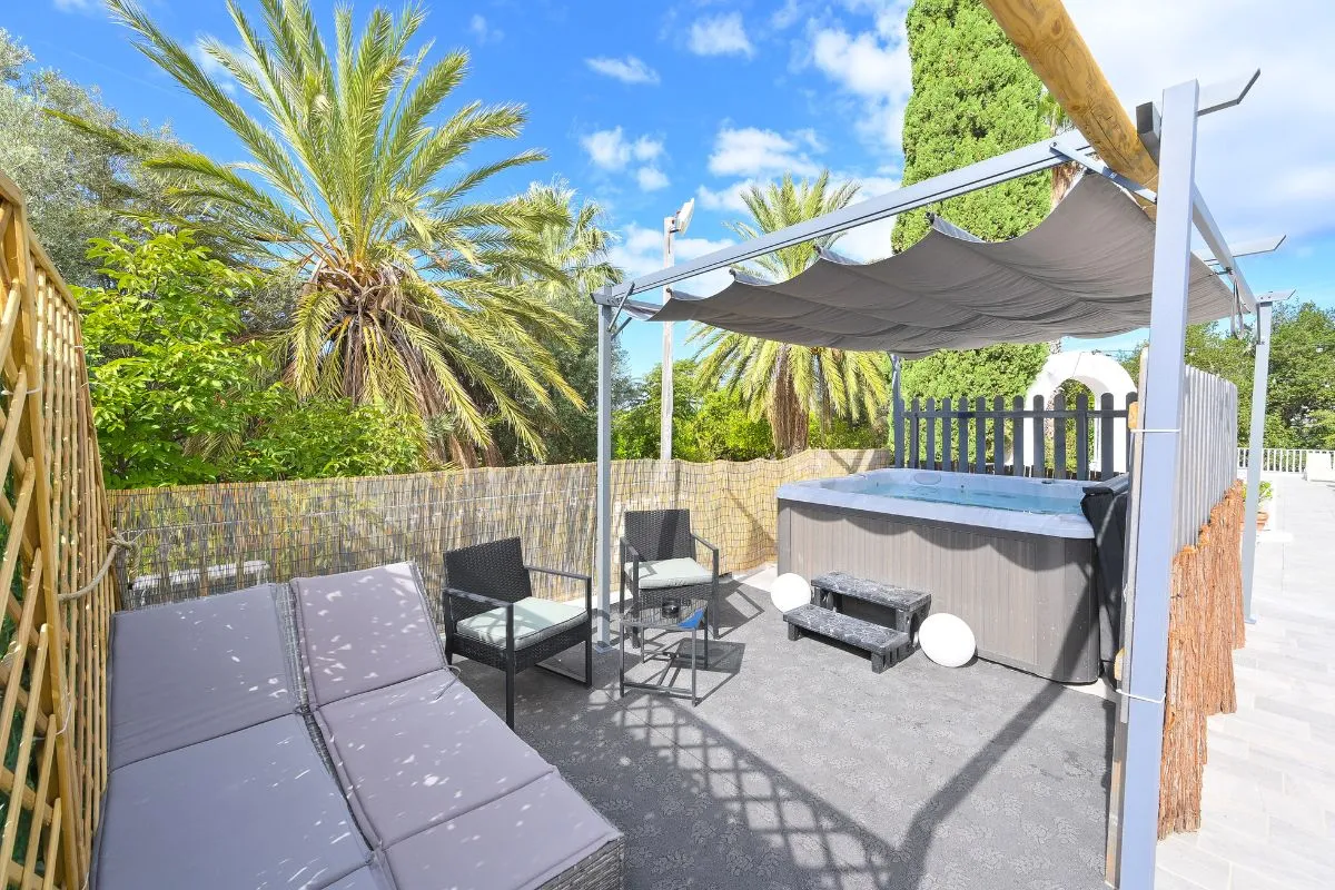Terrazza privata con vasca idromassaggio, lettini e pergolato tra le palme