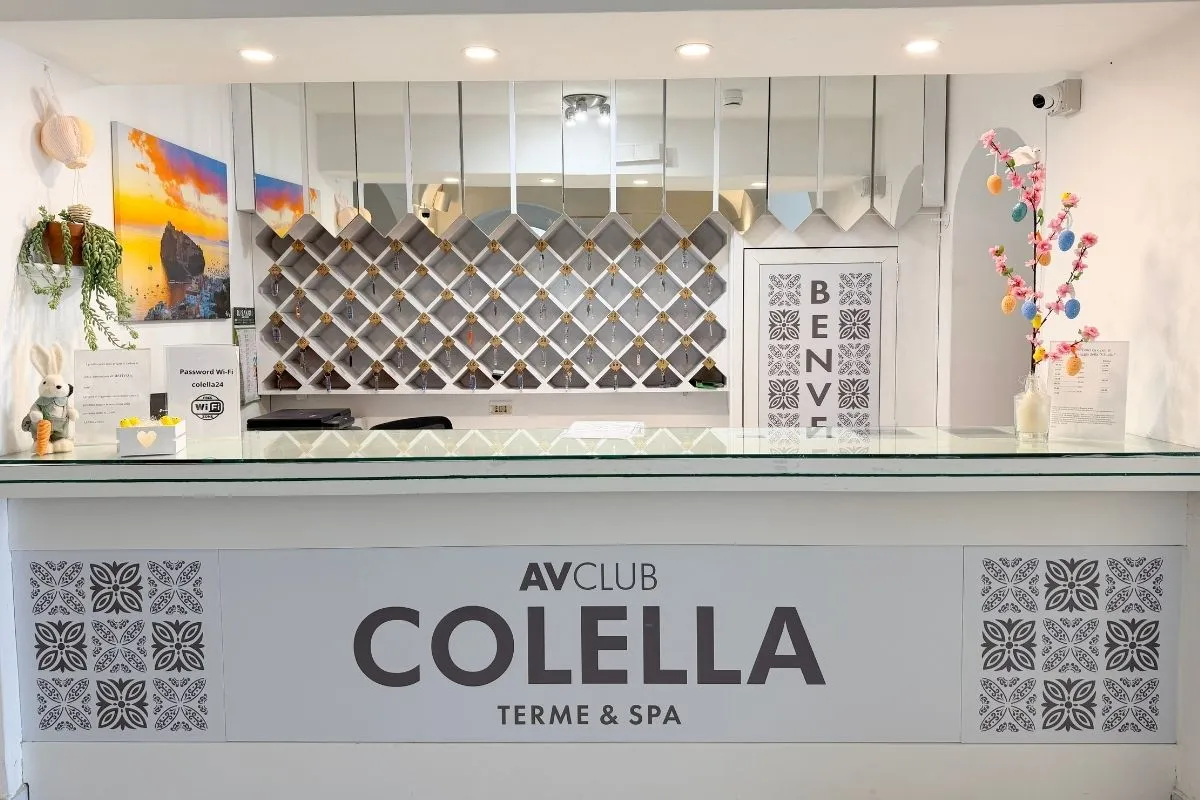 Reception dell'hotel con banco bianco e insegna AV Club Colella Terme & Spa