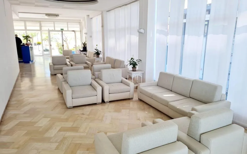 Ampia hall con poltrone bianche e pavimento in parquet chiaro