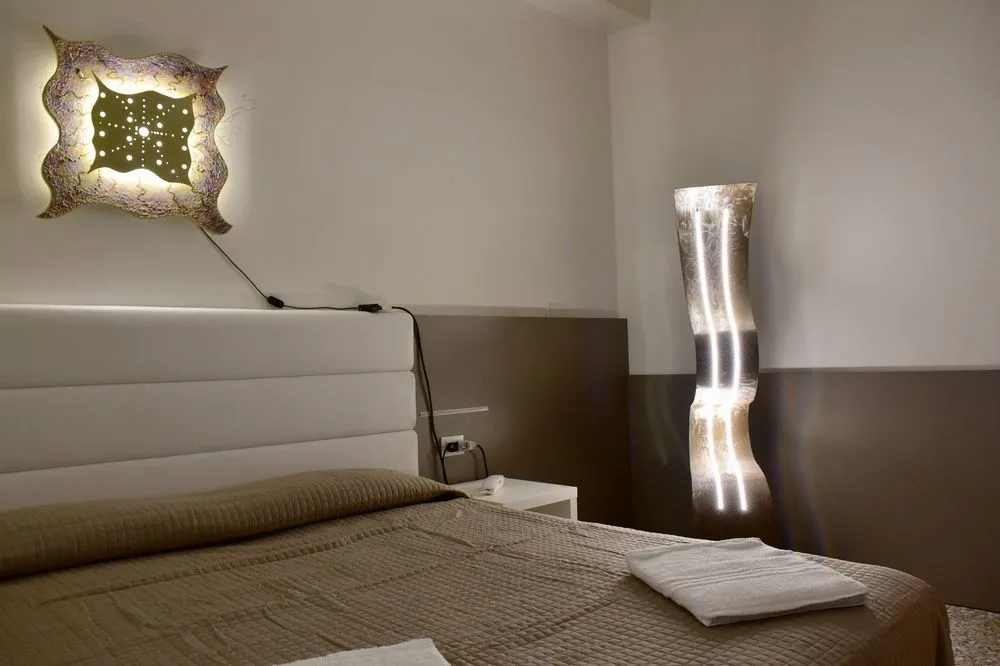 Dettaglio di camera con letto matrimoniale, lampada di design e applique luminosa