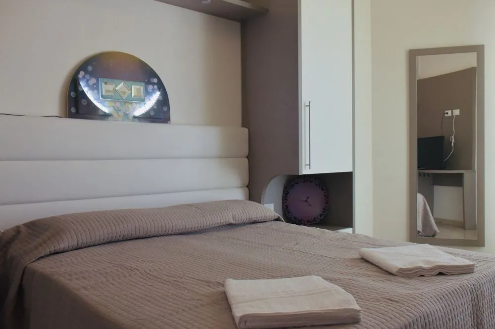 Camera matrimoniale con testiera imbottita, specchio e asciugamani sul letto