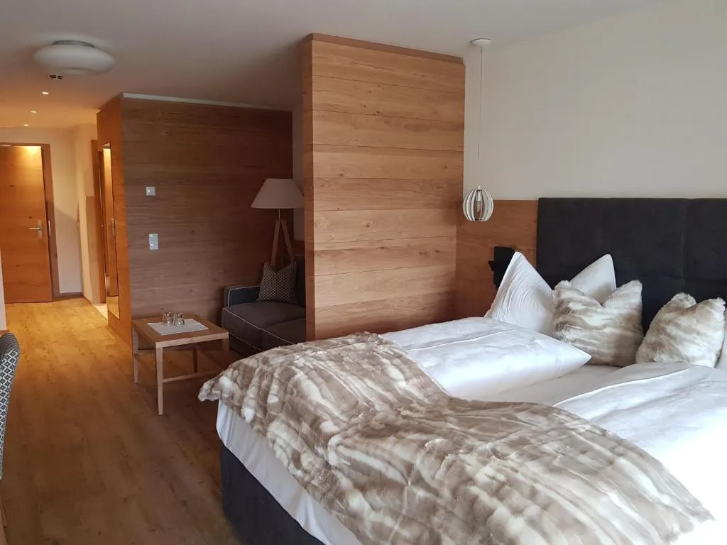 Camera moderna con parete in legno, letto matrimoniale con plaid in pelliccia e divanetto