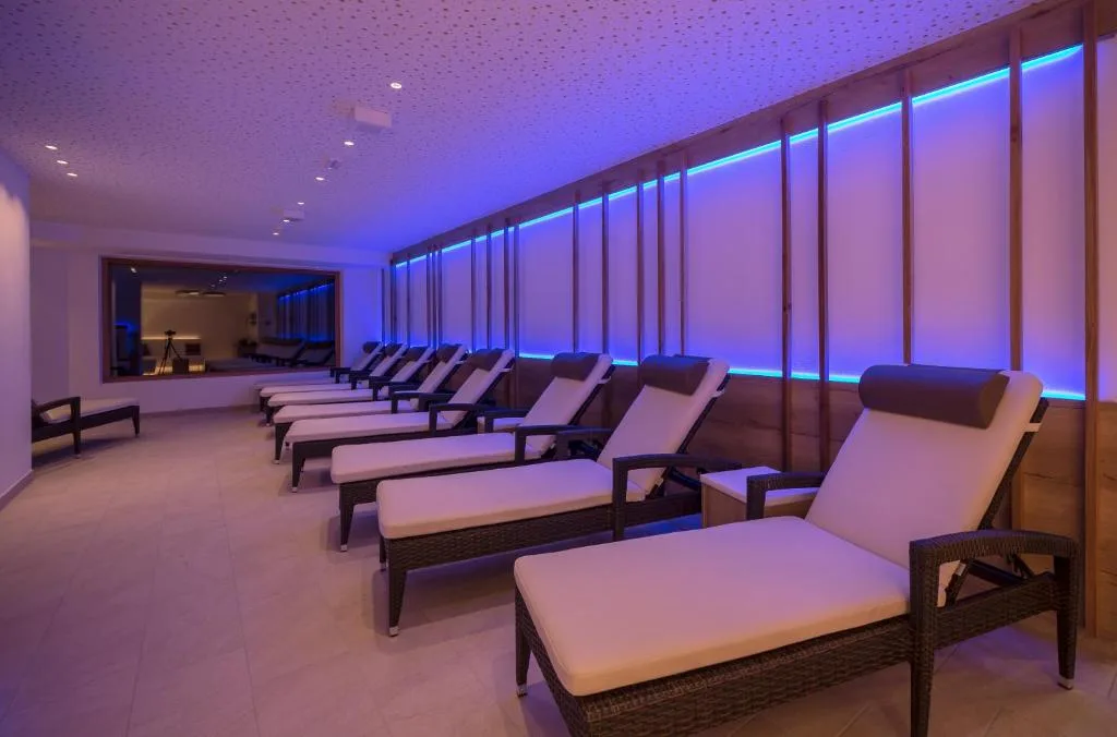 Area relax della spa con lettini in vimini e illuminazione LED blu lungo la parete