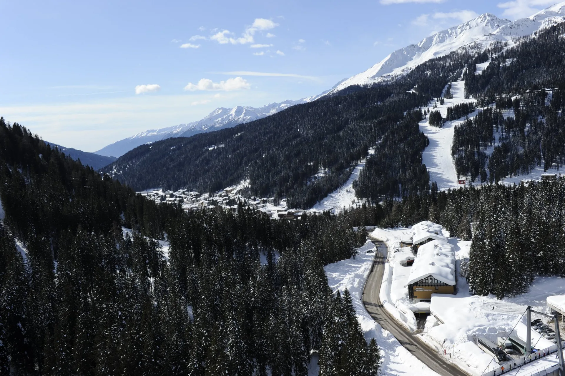 Veduta panoramica aerea della valle innevata con bosco di abeti e piste da sci