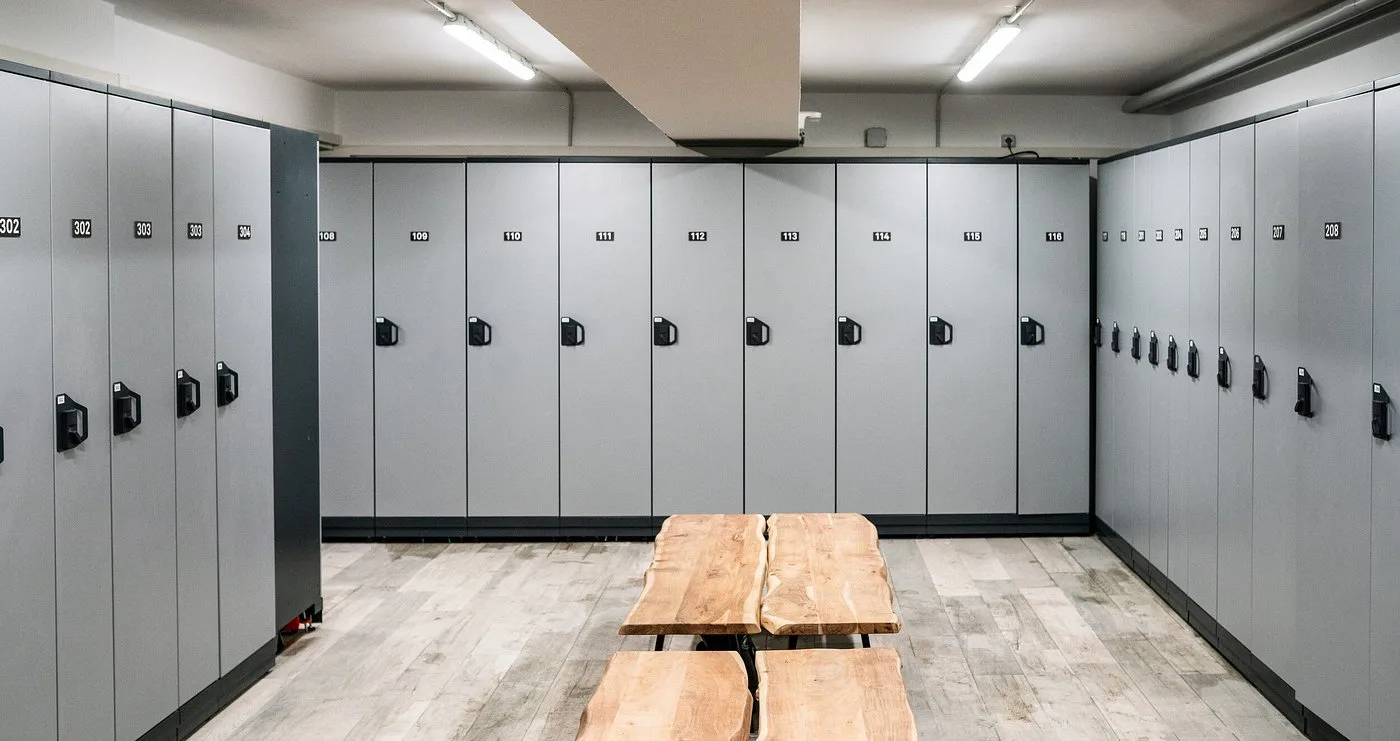 Spogliatoio con armadietti grigi numerati e panche in legno