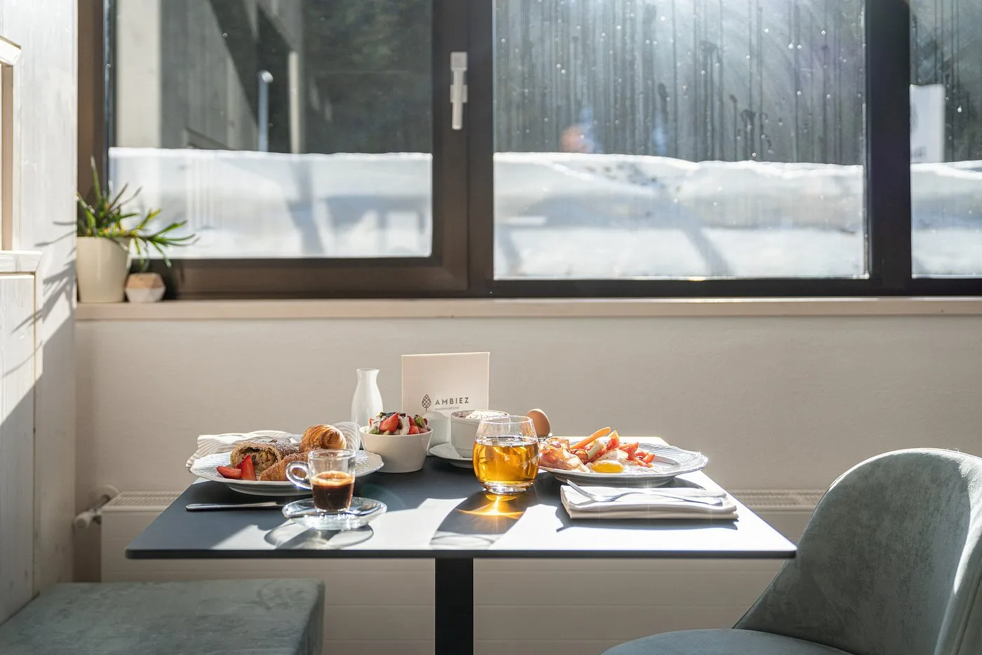 Tavolo apparecchiato per la colazione con vista sulla neve attraverso la finestra