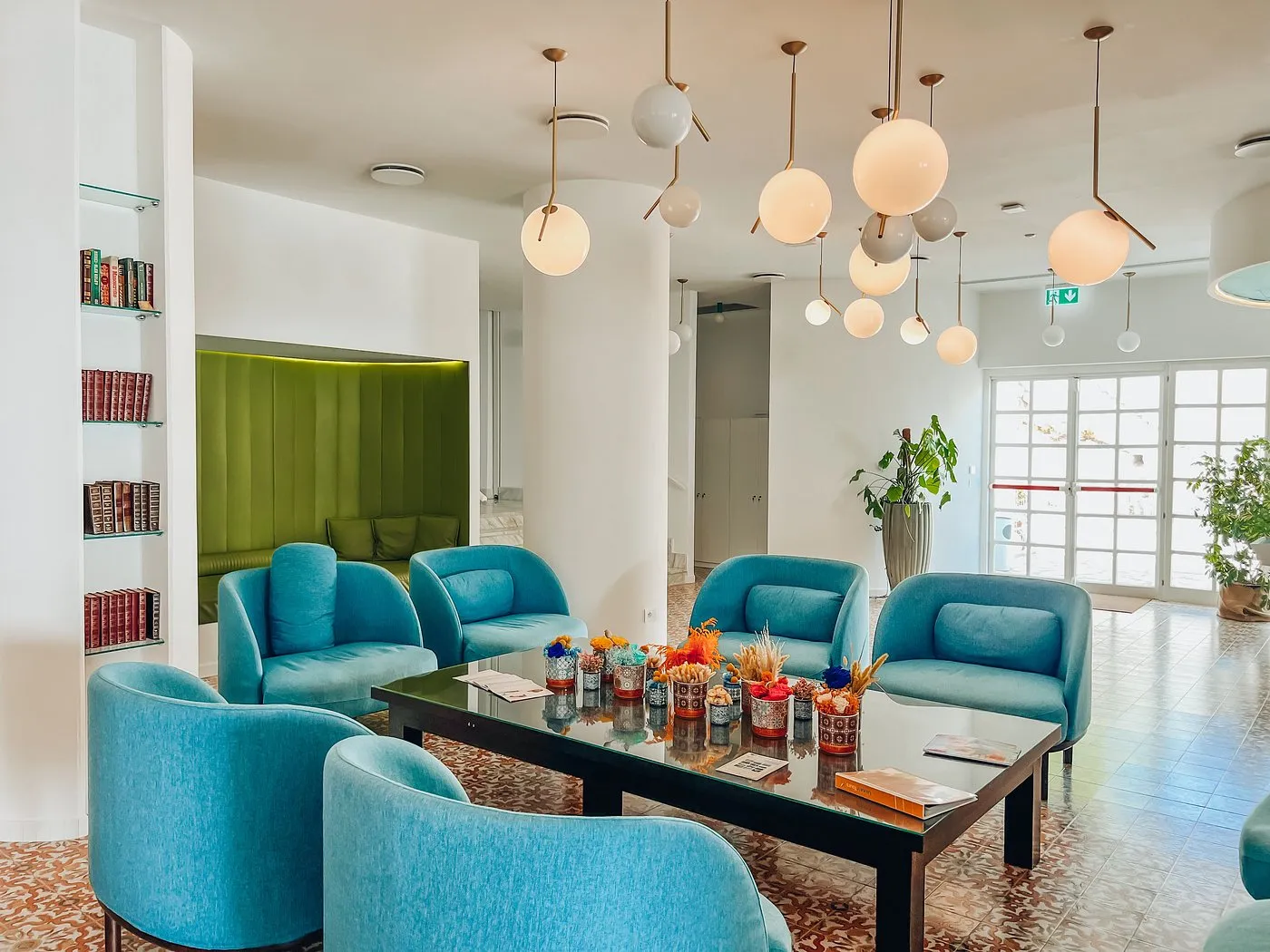 Hall dell'hotel con poltrone azzurre, tavolino e lampade sospese