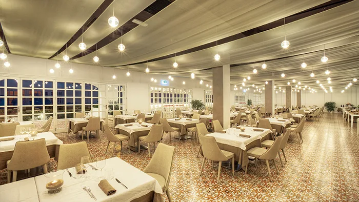 Sala ristorante interna con tavoli apparecchiati e luci sospese