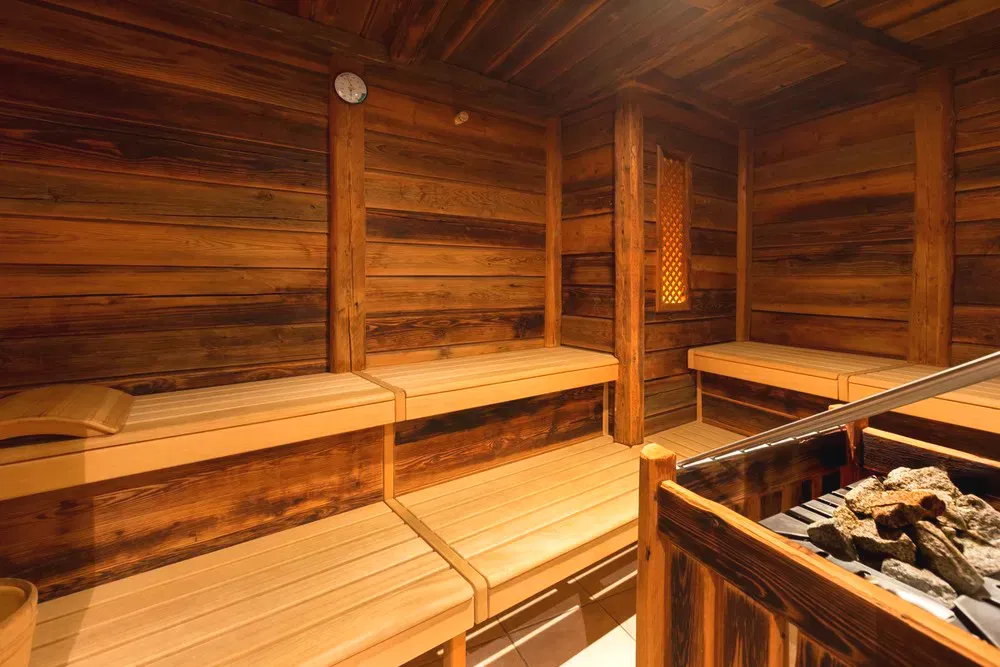 Interno di una sauna finlandese con panche in legno e stufa con pietre