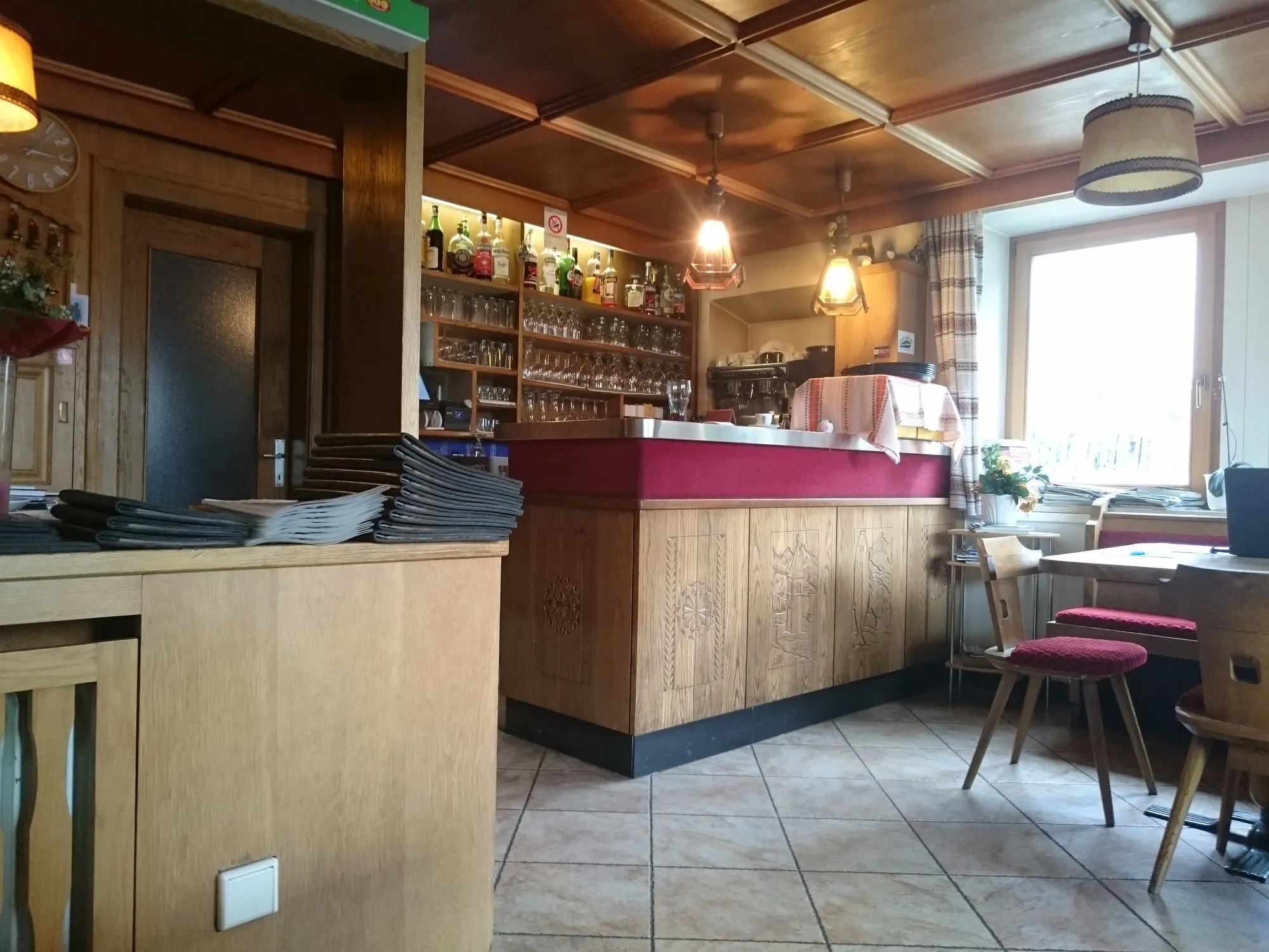 Bar dell'hotel con bancone in legno, bottiglie e bicchieri in stile tradizionale