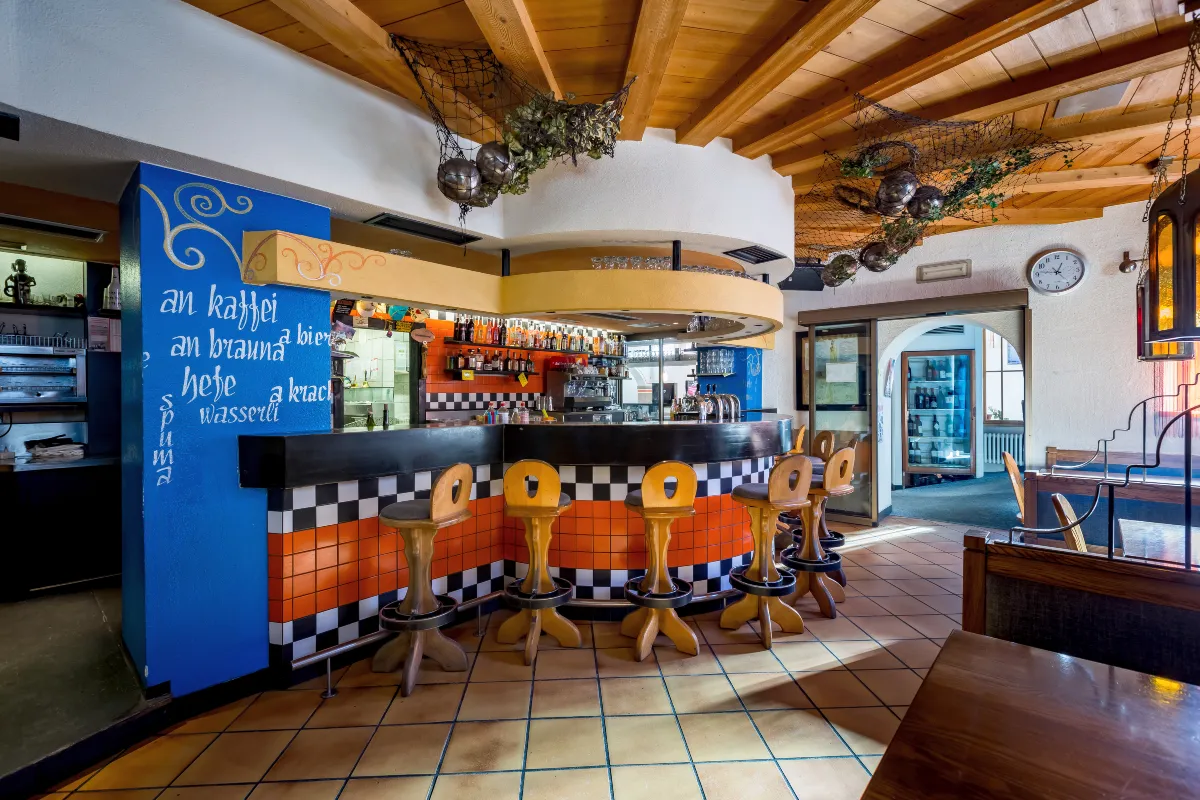Bar colorato dell'hotel con sgabelli in legno e bancone a scacchi arancione e nero