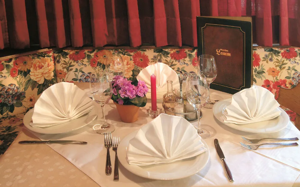 Tavolo del ristorante apparecchiato con tovaglioli bianchi piegati a ventaglio e menù