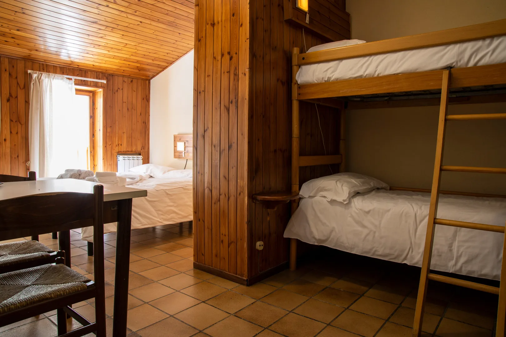 Camera rustica con letto matrimoniale, letto a castello e zona pranzo in legno