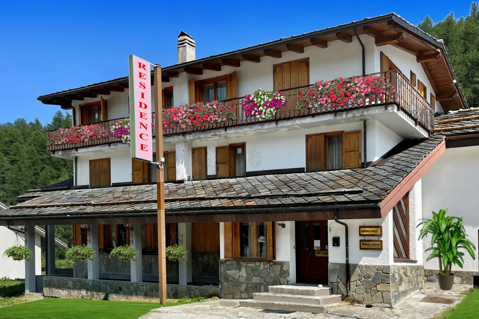 Facciata estiva del residence alpino con balconi fioriti e insegna Residence
