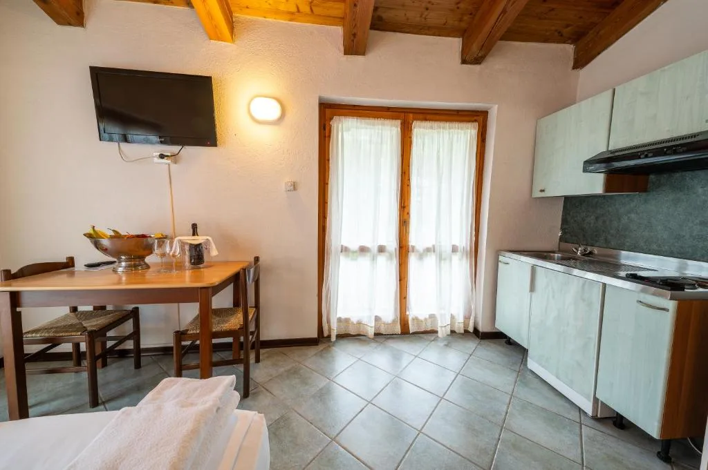 Angolo cottura con cucinino, TV a parete e zona pranzo con tavolo in legno