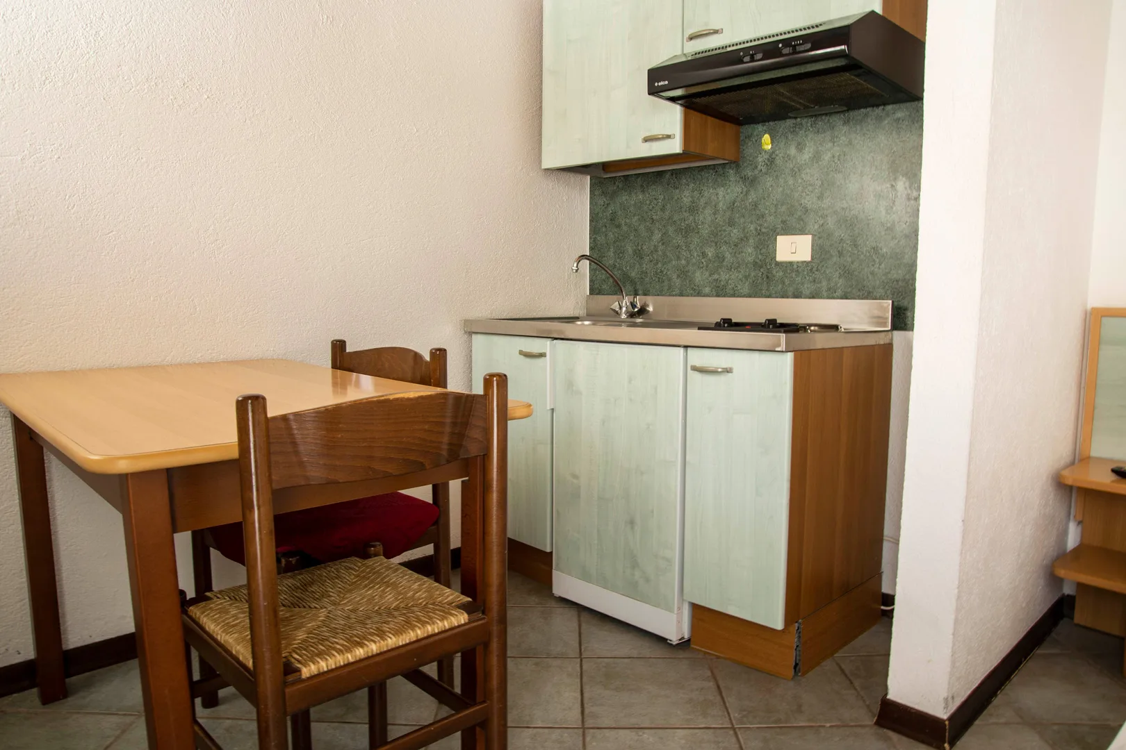 Cucinino compatto con lavello, fornelli e tavolo da pranzo in legno