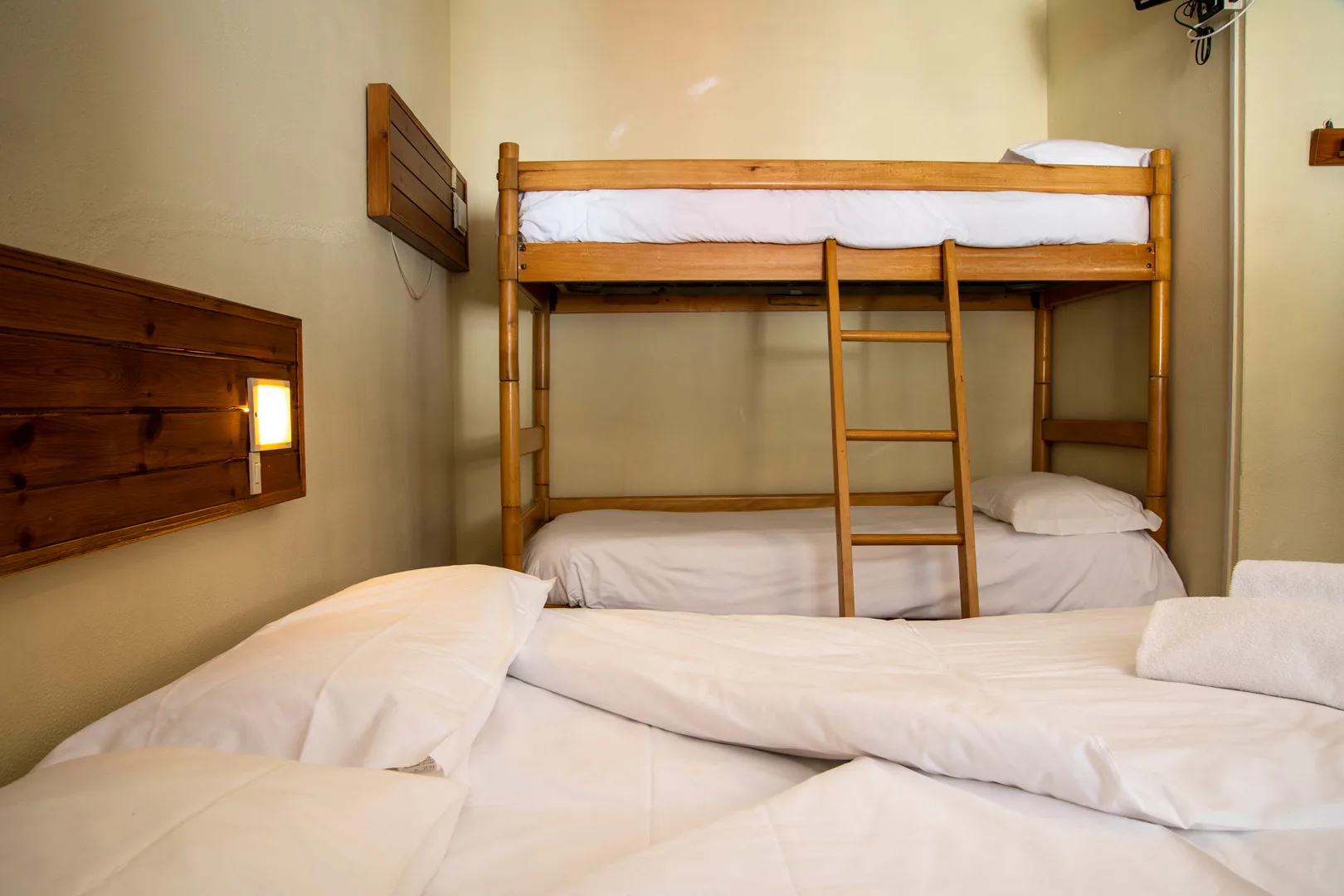 Camera con letto matrimoniale e letto a castello dalle testate in legno