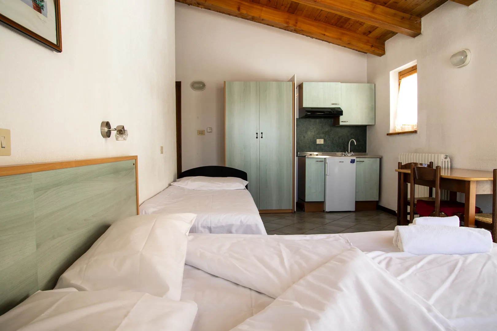 Monolocale con letti, armadio e cucinino integrato sotto il soffitto in legno