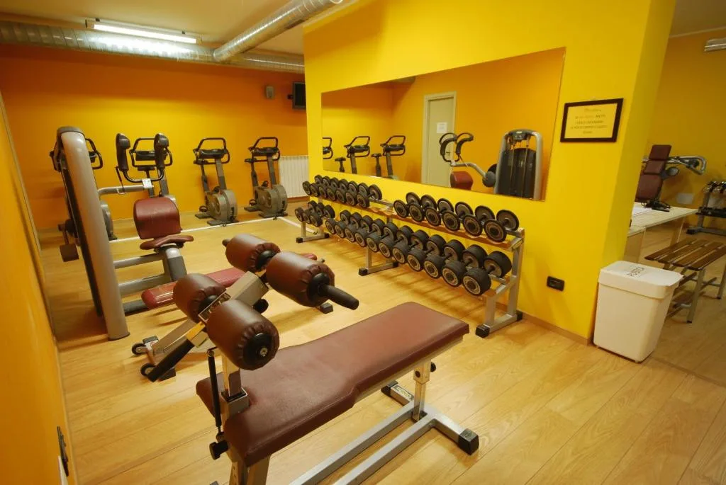 Palestra attrezzata con pesi e macchine cardio dalle pareti gialle
