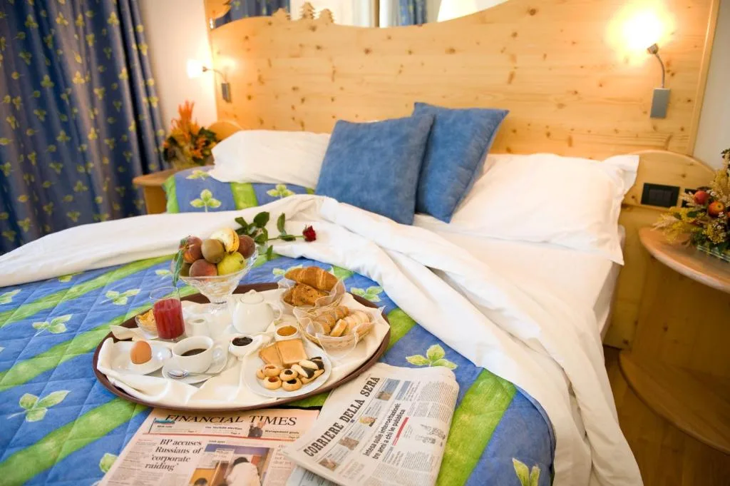 Colazione servita a letto con vassoio e quotidiani in camera alpina