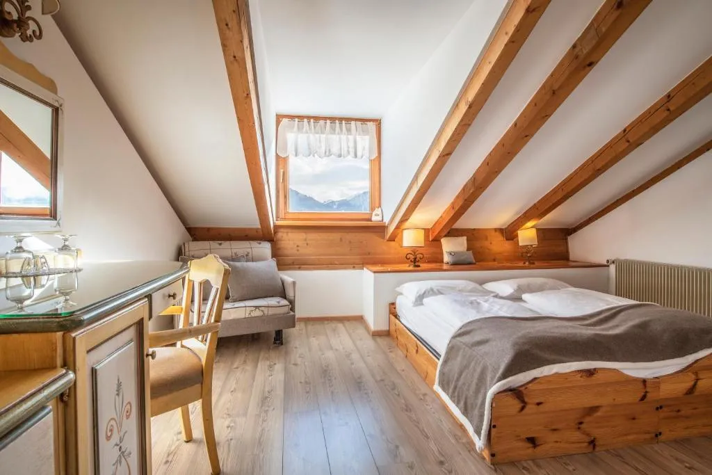 Camera mansardata con letto matrimoniale, travi a vista e scrivania