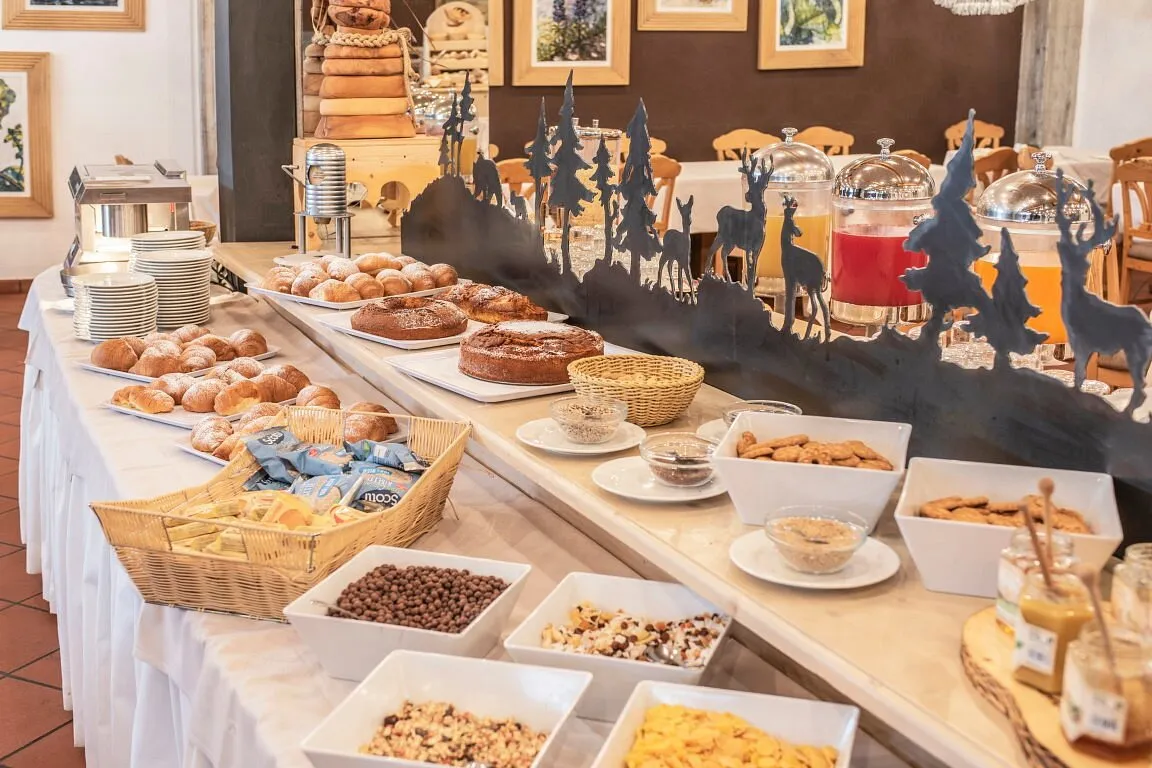 Buffet della colazione con cornetti, torte, cereali, succhi di frutta e miele in ambiente decorato in stile montano