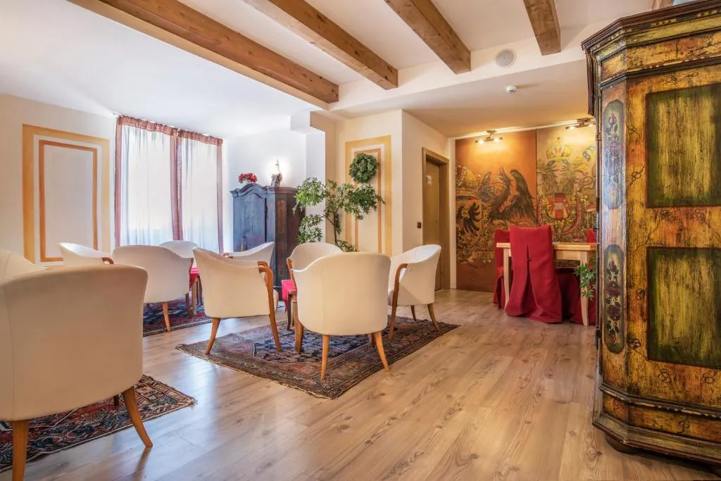 Sala soggiorno con poltrone bianche, travi a vista e mobili antichi dipinti