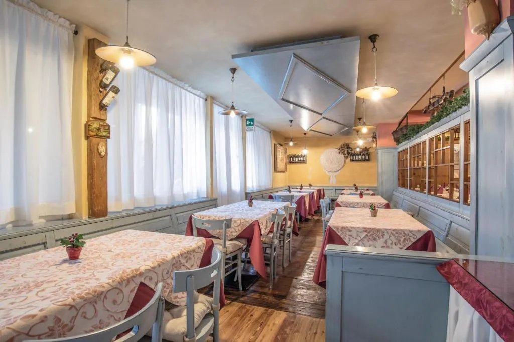 Sala ristorante con tavoli apparecchiati, tovaglie rosa e boiserie chiara