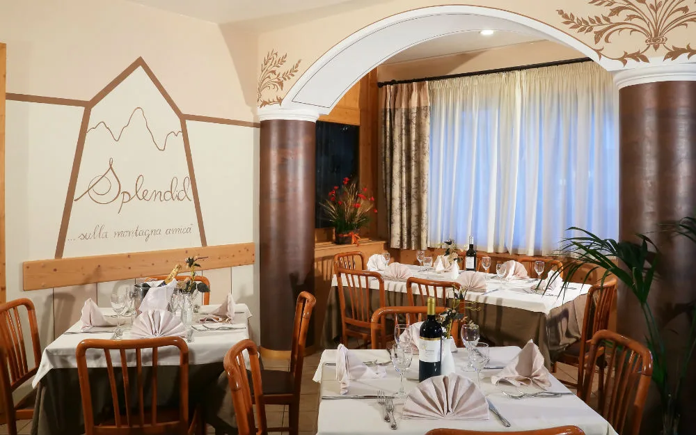 Sala da pranzo elegante con tavoli apparecchiati e logo Splendid sulla parete