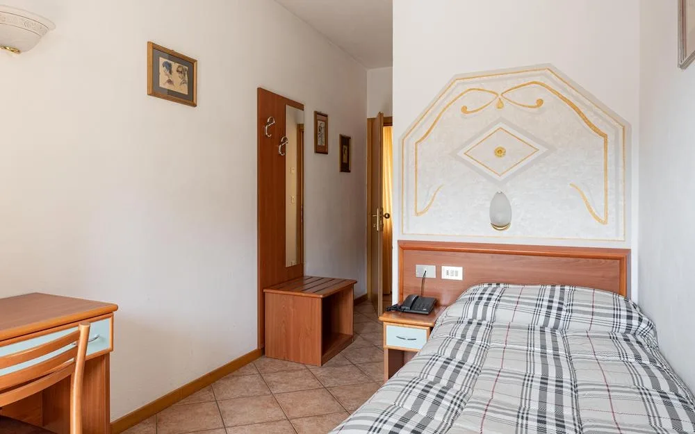 Camera singola con letto, scrivania e decorazione a parete