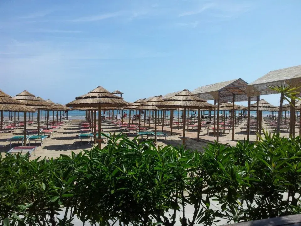 Vista sulla spiaggia con ombrelloni di paglia e lettini affacciata sul mare