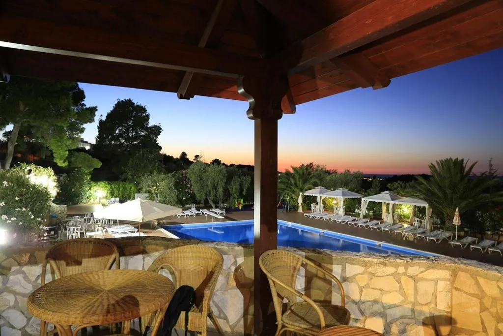 Terrazza con tavoli in vimini affacciata sulla piscina al tramonto
