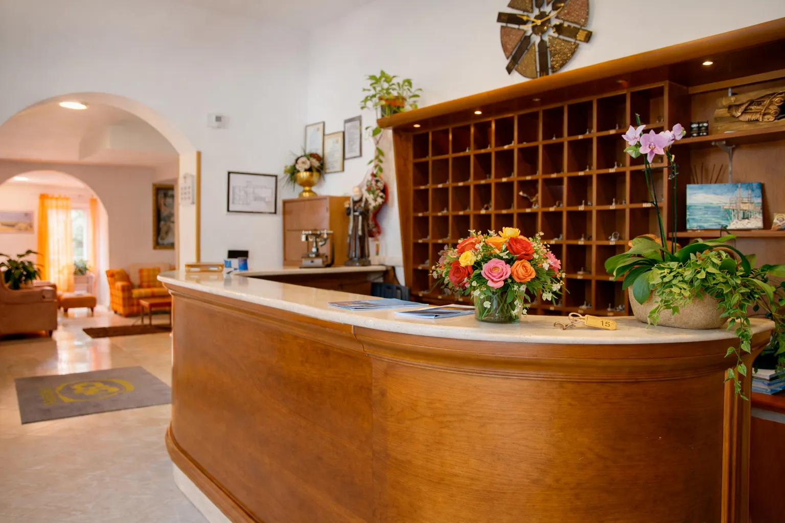 Reception dell'hotel con bancone in legno e composizione di fiori colorati