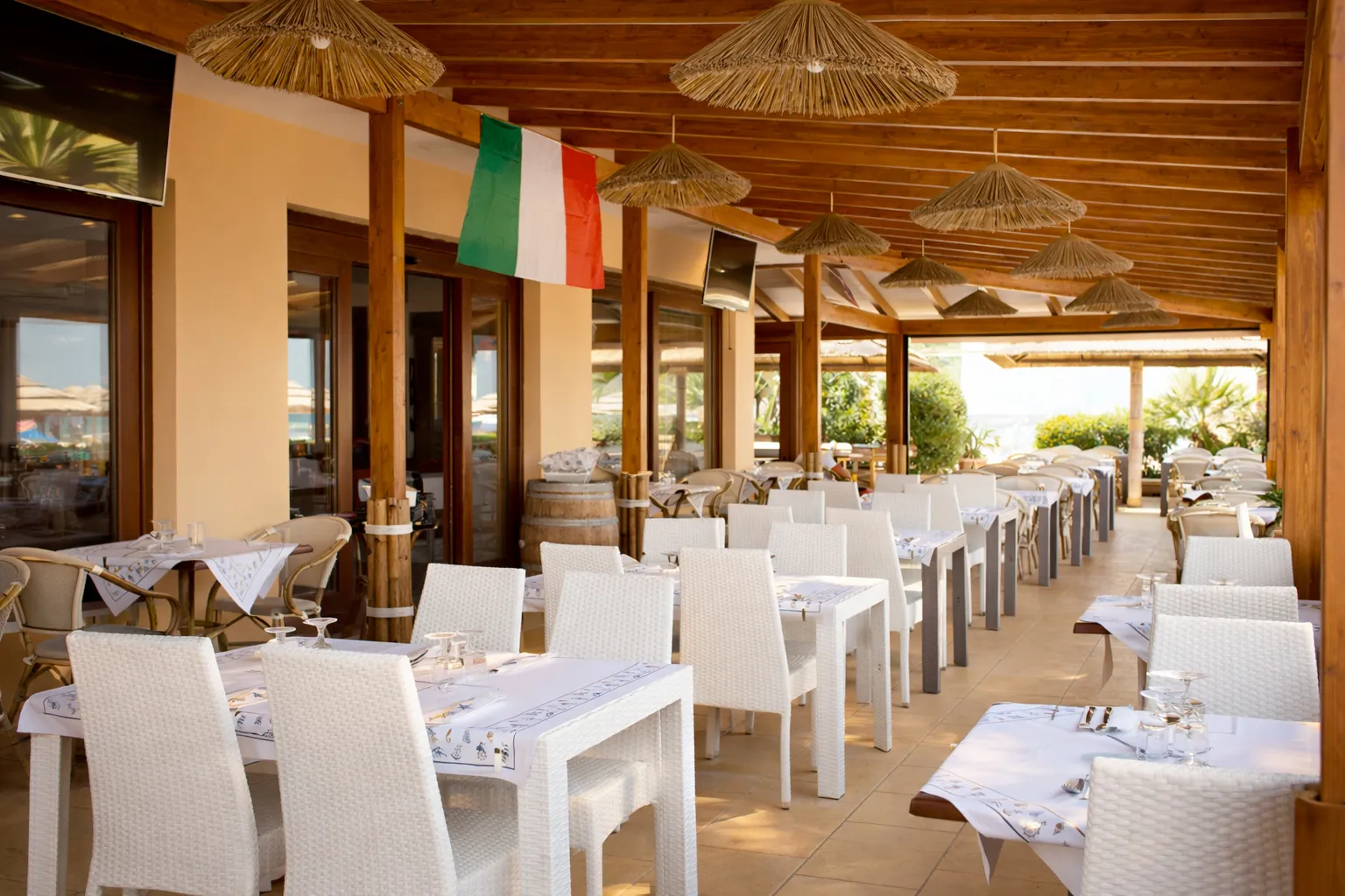Ristorante esterno coperto con tavoli bianchi e bandiera italiana