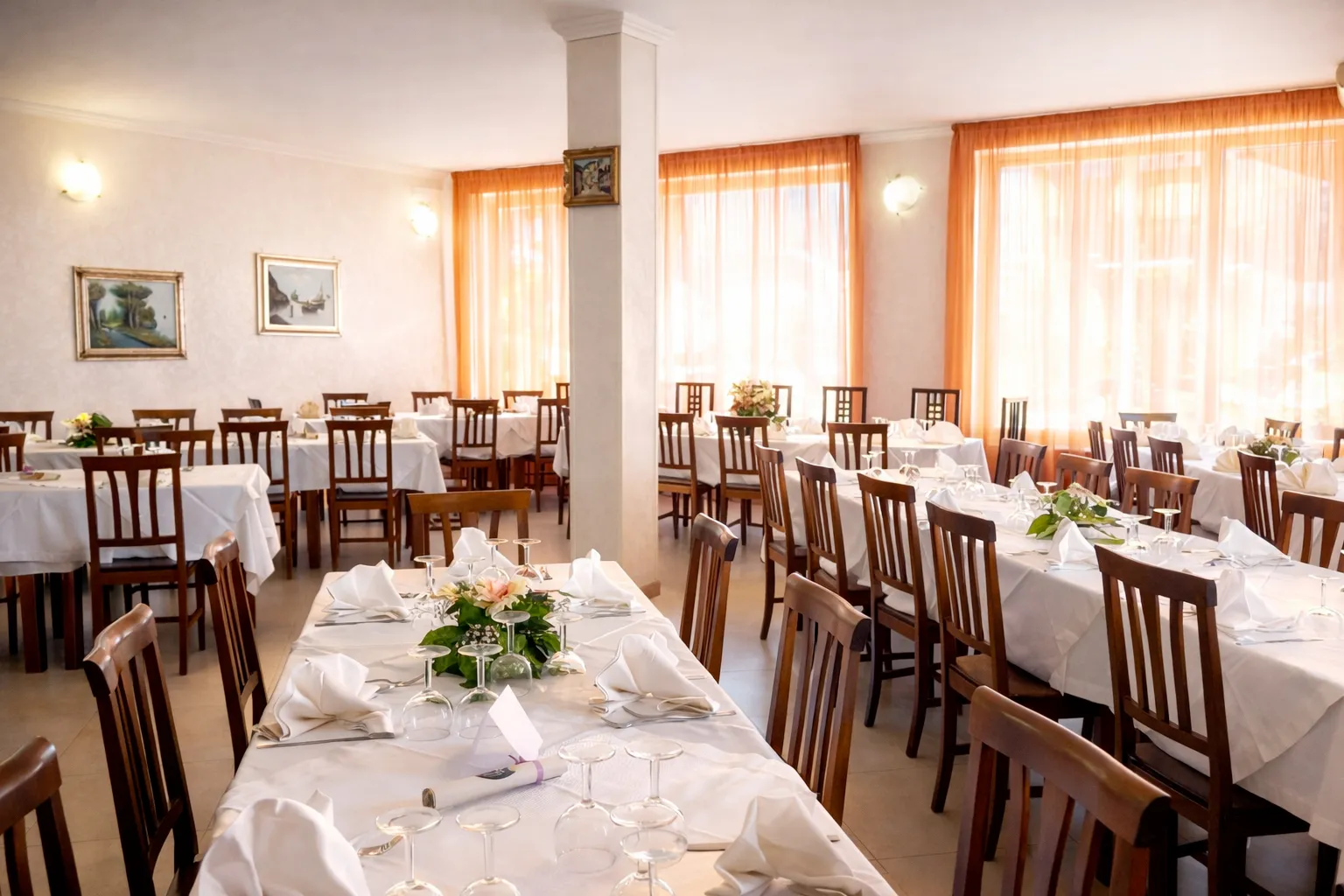 Sala ristorante interna con tavoli apparecchiati e tende arancioni