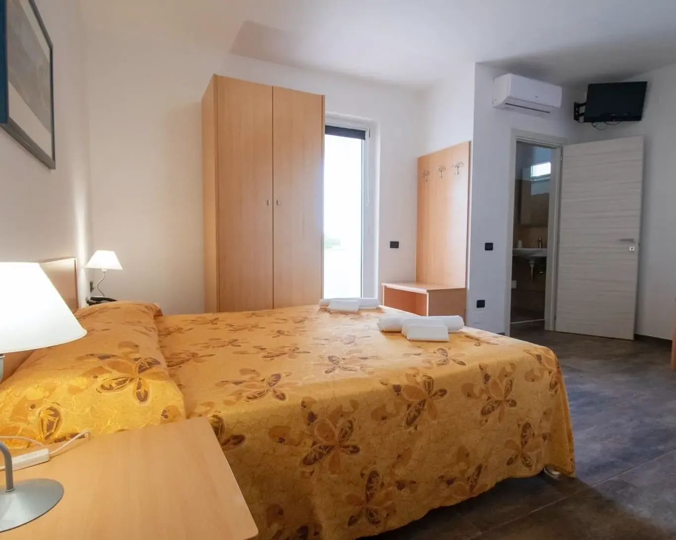 Camera matrimoniale con copriletto giallo a fiori e aria condizionata